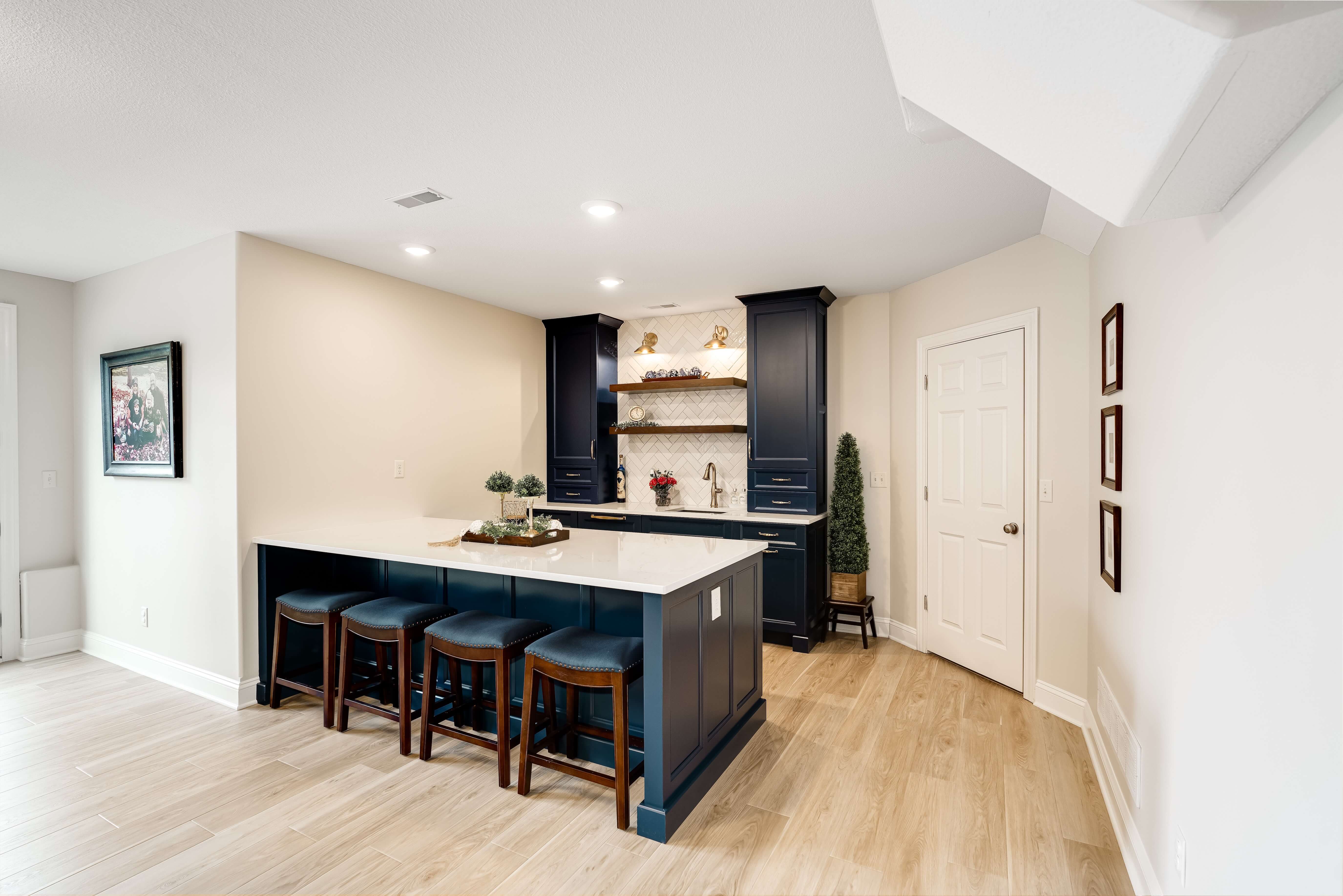 Basement kitchenette in Bloomington Normal with navy cabinets and bar seating