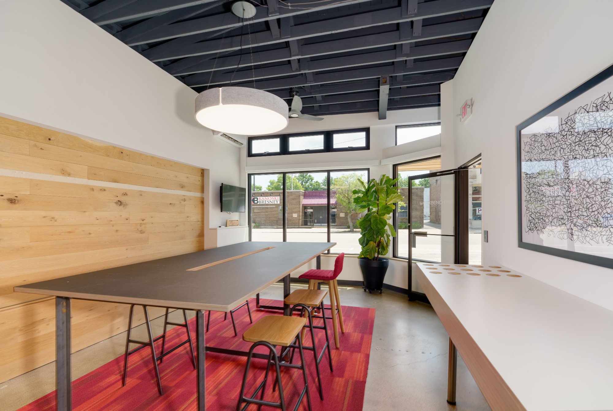 Workbench-Architects-collaborative-meeting-room-with-dark-worktable-wood-accent-wall-and-storefront-windows
