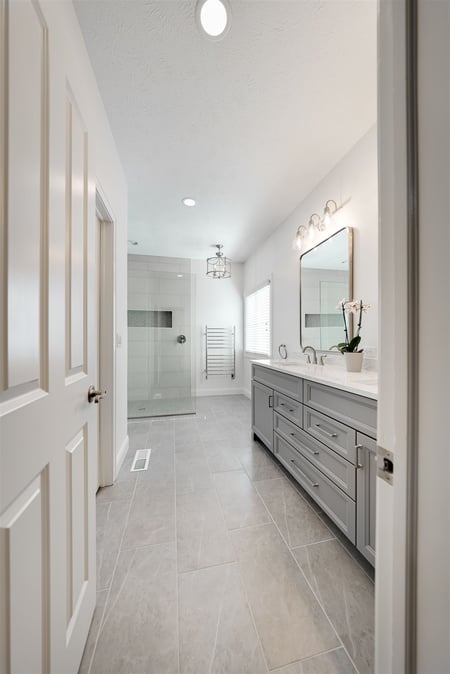 bathroom remodel with open door showcasing walk-in shower and double vanity