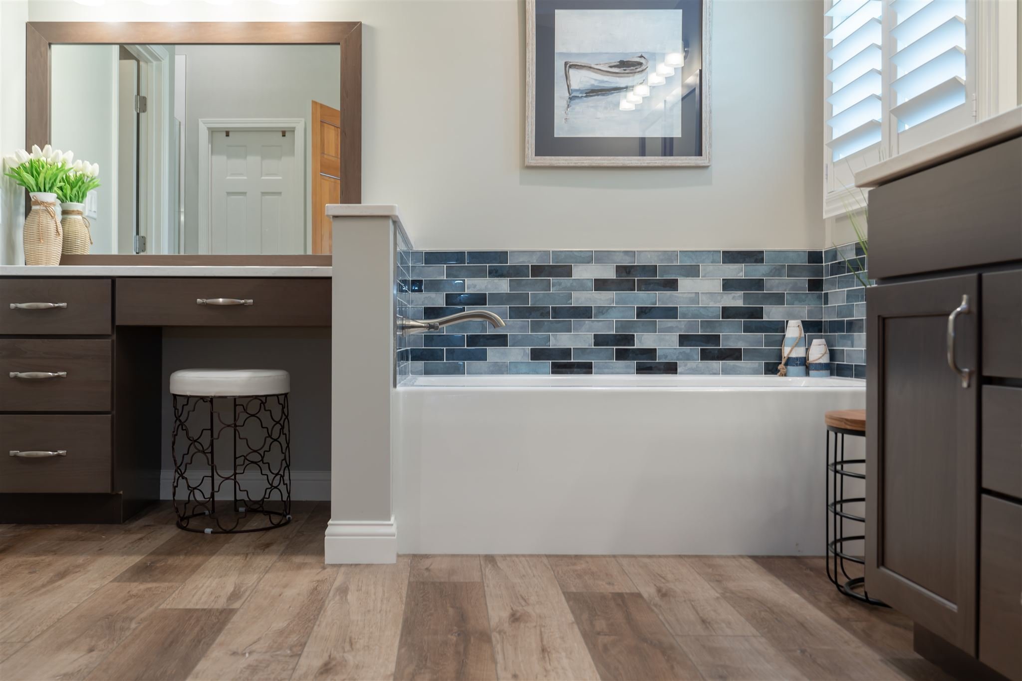 Bathroom with blue tile tub surround, wood flooring, and vanity, built by Landmark Construction and located in Illinois