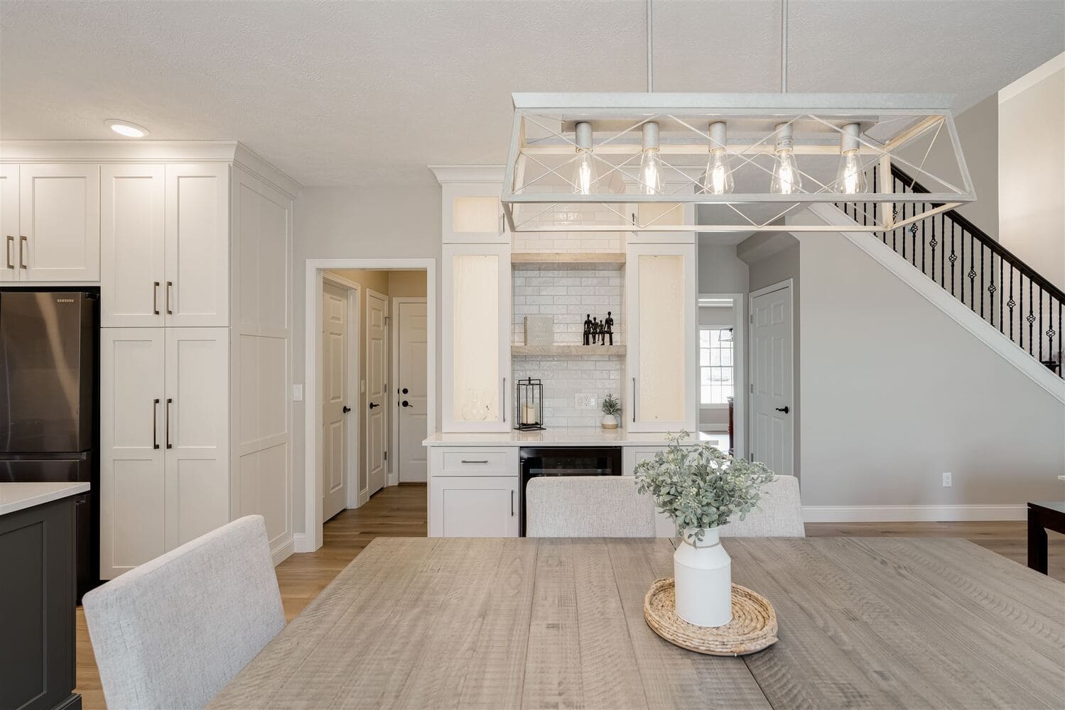Dining area in Bloomington Normal with wood table, modern chandelier, built in bar, and staircase nearby