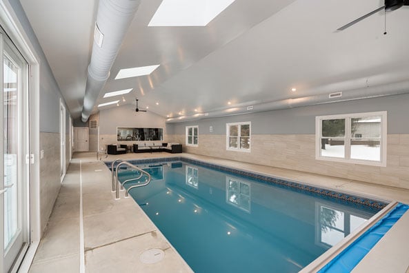 Indoor pool house with skylights, lounge seating, and large windows, built by Landmark Construction and located in Illinois
