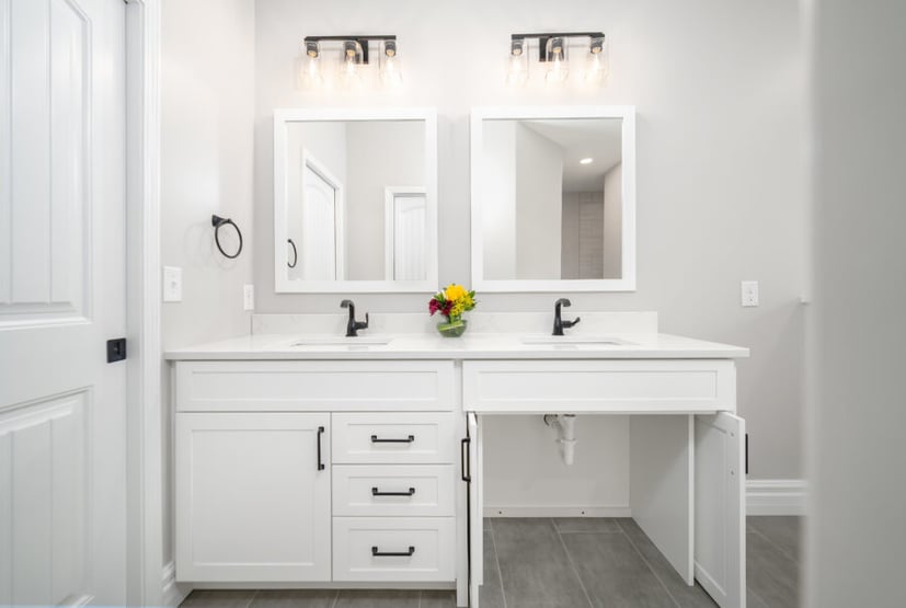 White double vanity in Bloomington Normal with black faucets, twin mirrors, and open cabinet under right sink
