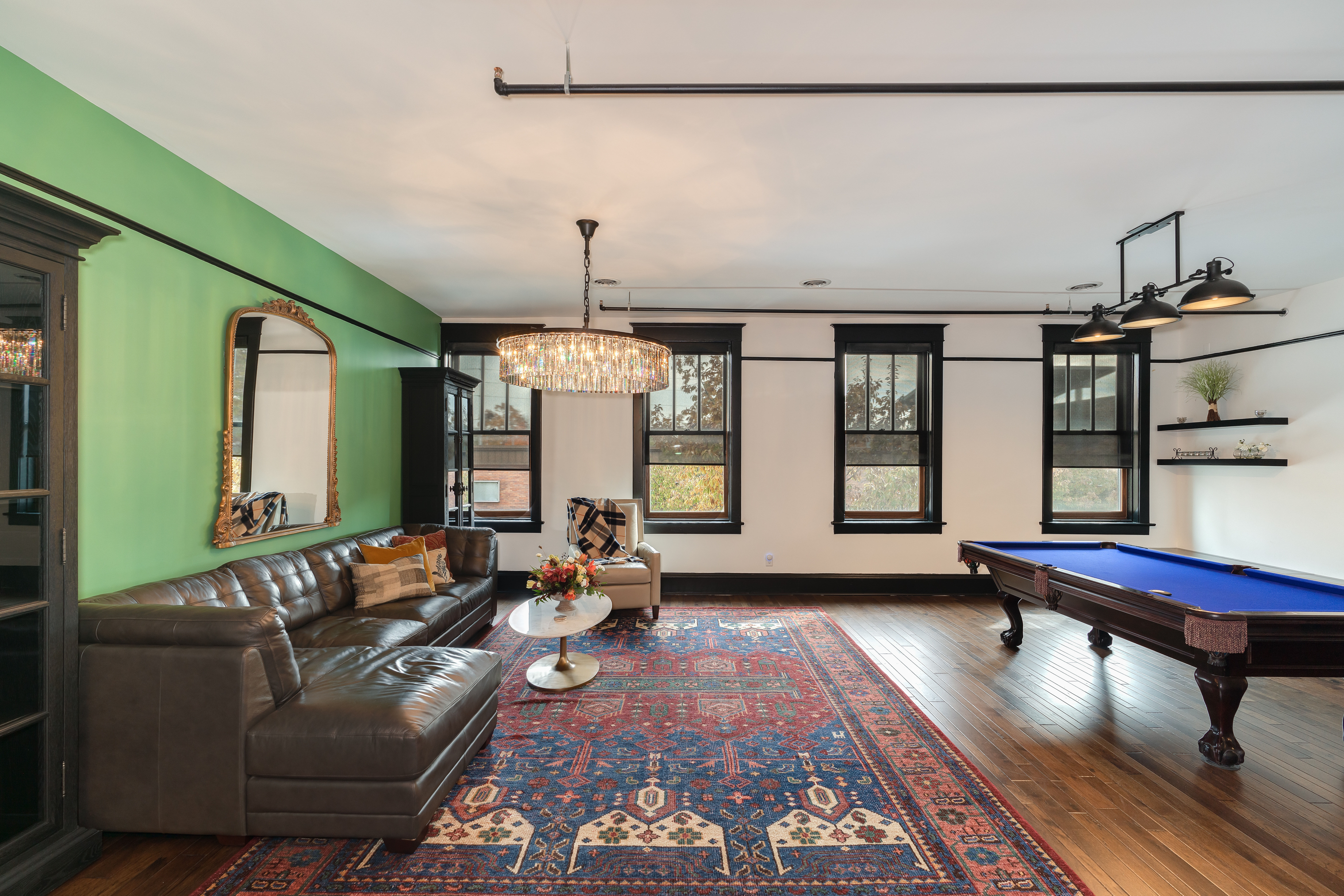 Open entertaining space featuring hardwood floors, hanging lighting, and a pool table 