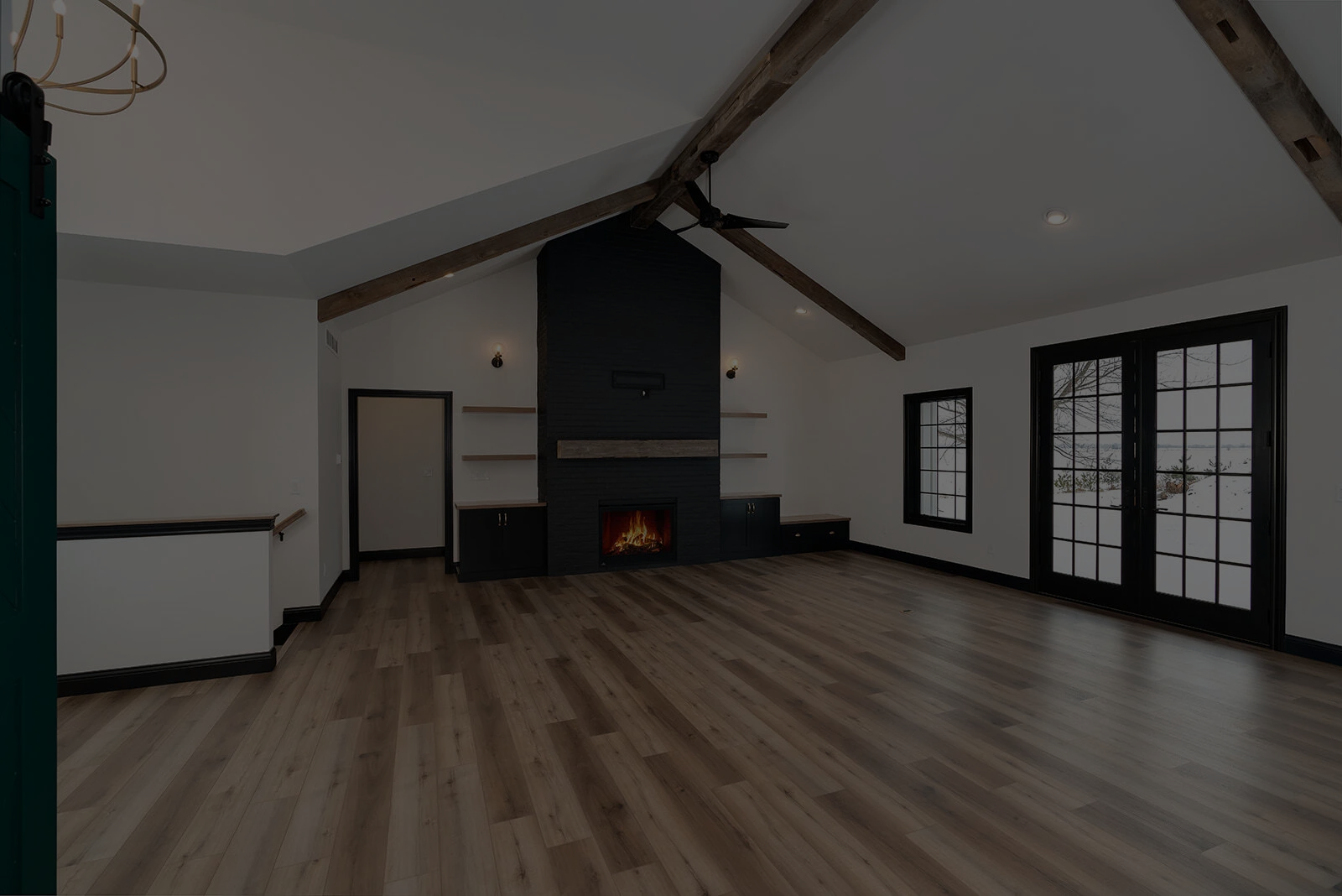 Vaulted living room in Bloomington Normal with exposed beams, black fireplace and wide plank floors